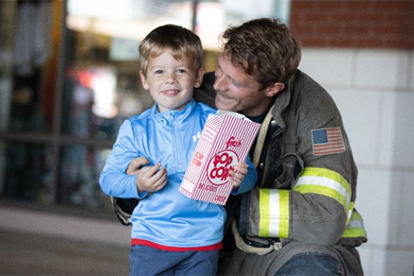 firefighter posing with his little boy, eating popcorn, mental health awareness for first responders