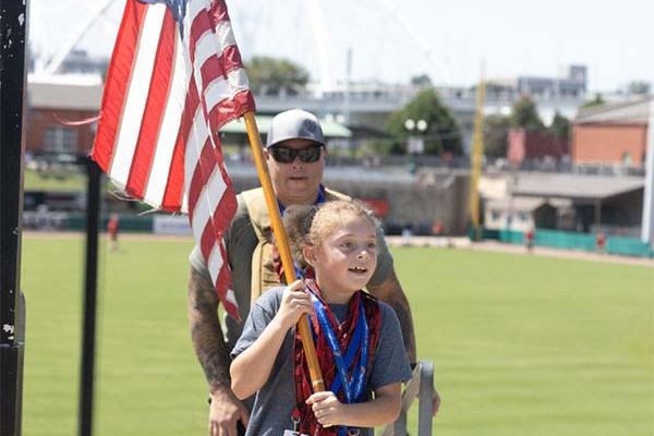 little girl carrying flag up a flight of stairs, first responder ptsd treatment programs 